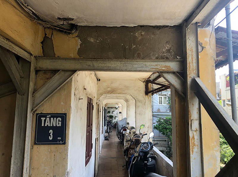 Cải tạo nhà tập thể cũ 40m2 khi hành lang chung của khu nhà tập thể cũ, với sàn và tường bị ố vàng, bong tróc. Khung dầm bằng thép lộ ra, bị rỉ sét.