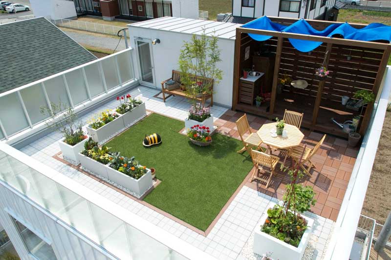 Sân thượng được cải tạo với khu vườn nhỏ, thảm cỏ nhân tạo, bàn ghế gỗ và giàn che nắng, giúp không gian sinh hoạt ngoài trời thoáng mát và bền vững hơn.