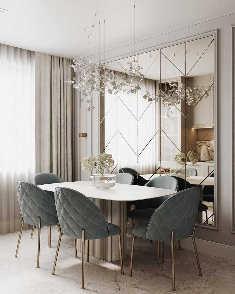 Khu vực phòng ăn sang trọng sau khi sửa nhà cấp 4 80m2 nổi bật với gương trang trí lớn có hoa văn hình học, bàn ăn oval và những chiếc ghế nhung màu xanh xám thanh lịch.